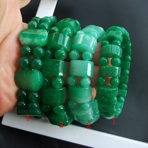 Könnte beinhalten: Vier Jade-Armbänder in Grün mit verschiedenen Perlenstilen. Die Armbänder sind übereinander gestapelt, wobei die Zahlen 1, 2, 3 und 4 am unteren Rand des Bildes sichtbar sind.