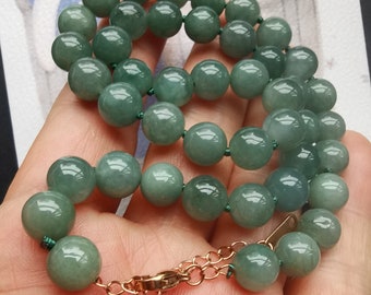 Puede incluir: Un collar de cuentas de jade verde con un cierre de oro. El collar está hecho de cuentas redondas y está enhebrado en un cordón verde.