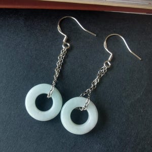Könnte beinhalten: Ein Paar silberne Ohrringe mit einem Anhänger aus hellgrünem Jade-Ring an jedem Ohrring.