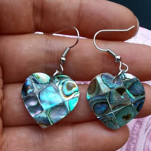Peut inclure: Une paire de boucles d'oreilles en argent en forme de cœur avec des incrustations d'abalone irisé. Les boucles d'oreilles ont une fermeture à crochet en argent.