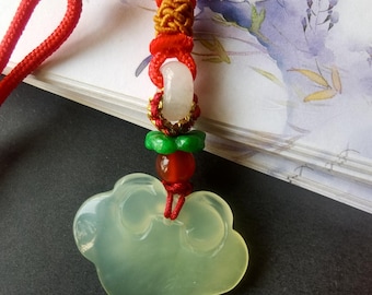 May include: A jade cloud pendant with a red cord. The pendant is a pale green color and has a smooth, polished surface. The cord is red and has several decorative beads in red, green, and gold.