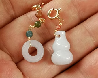 May include: A white jade gourd charm with a gold clasp and a chain of green, brown, and pink beads. The charm is attached to a gold chain.