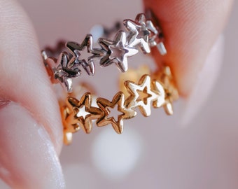 May include: Two gold and silver rings with star cutouts. The rings are stacked on top of each other.