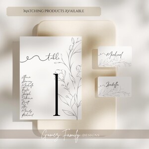 May include: A white card with a black floral design and the word "table" written in cursive. The card also has a black number "1" and a list of names. Two smaller white cards with floral designs and the names "Michael" and "Isabella" written in cursive.