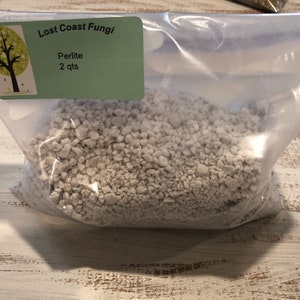 May include: A clear plastic bag filled with white perlite, a lightweight aggregate used in gardening. The bag has a label that reads "Lost Coast Fungi" and "Perlite 2 qts".