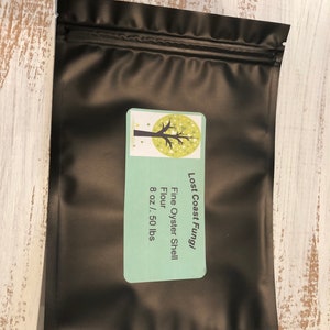 May include: Black resealable pouch with a white label that says "Lost Coast Fungi" and "Fine Oyster Shell Flour 8 oz / .50 lbs".