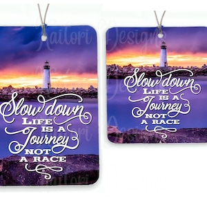 May include: A purple and blue sunset over a body of water with a lighthouse in the distance. The text "Slow down Life is a Journey Not a Race" is written in white cursive font.