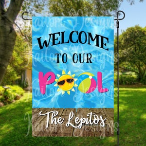 May include: Welcome to our pool garden flag with a blue pool background, a sun with sunglasses, a beach ball, and the text "The Lepitos" on a wood plank.