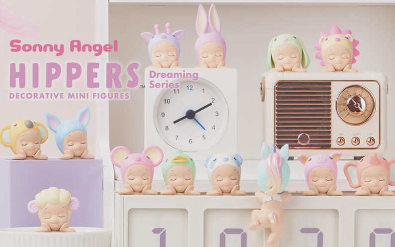Op de afbeelding: Een collectie van decoratieve Sonny Angel Hippers Dreaming Series mini-figuren met diverse personages in dierenthema hoofddeksels. De figuren staan opgesteld naast een witte analoge klok en een radio in vintage-stijl op een witte plank.