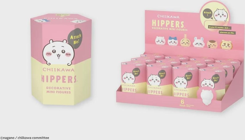 May include: Pink and yellow boxes and display featuring "Chikawa Hippers" decorative mini figures. The boxes and display have a cartoon character on them. The display has several cylindrical boxes with the same character. The text "Attach Me!" is on the boxes.