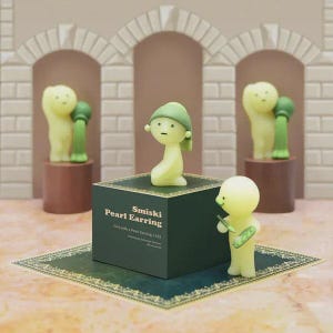 May include: A display of Smiski figurines. The central figure, wearing a green cap, sits on a dark green box labelled "Smiski Pearl Earring." Other figures stand on pedestals, and one holds a small object. The background features arched structures.