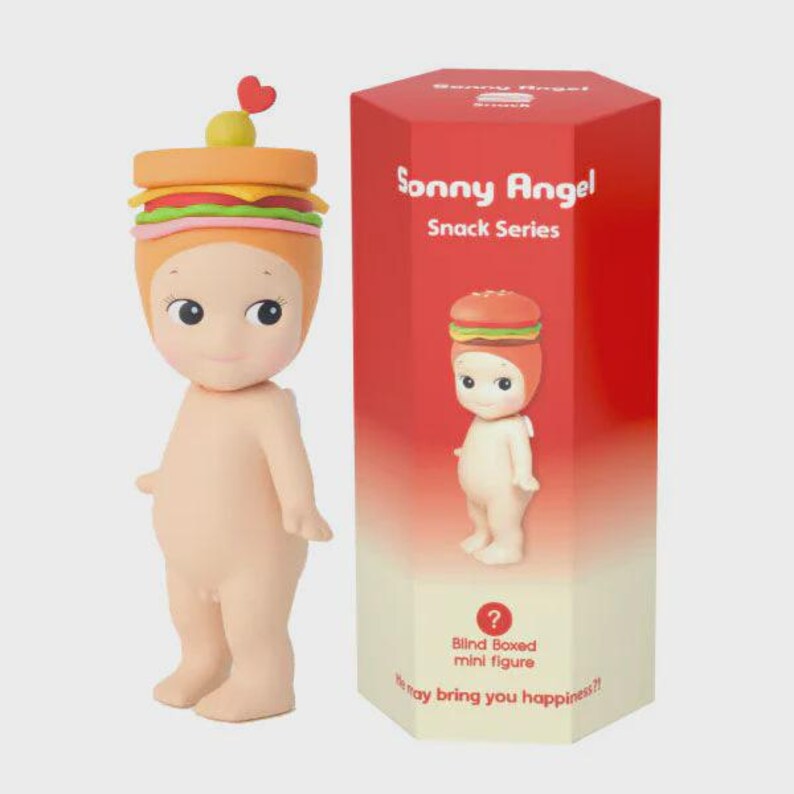 May include: A Sonny Angel mini figure from the Snack Series, featuring a burger-themed headpiece with a heart and olive. The figure is nude with a light skin tone, standing next to a red and white box with the series name and a burger illustration.