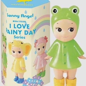May include: A Sonny Angel mini figure from the I Love Rainy Day Series, depicting a doll in a green frog hat, raincoat, and yellow wellington boots. The box displays other figures and the text "I Love Rainy Day Series".