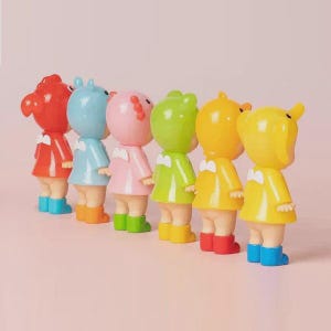 May include: Six brightly coloured figurines in a row. Each has a different coloured head and outfit, including red, blue, pink, green, and yellow. The figurines are wearing matching boots in various colours. Each has a white bow tie.