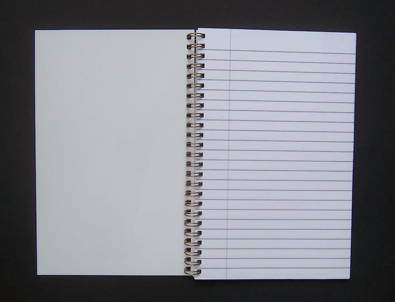 Pode incluir: Um caderno de espiral aberto com p&aacute;ginas pautadas &agrave; direita e p&aacute;ginas em branco &agrave; esquerda. O caderno tem uma encaderna&ccedil;&atilde;o prateada.