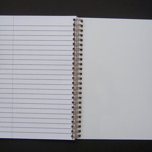 Pode incluir: Um caderno branco de espiral com p&aacute;ginas pautadas. O caderno est&aacute; aberto em uma p&aacute;gina em branco.