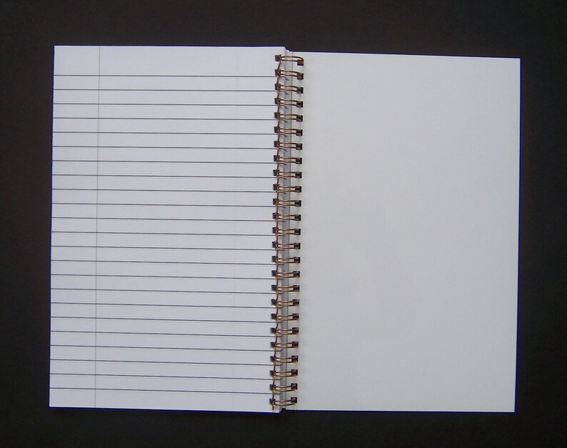 Pode incluir: Um caderno branco de espiral com p&aacute;ginas pautadas. O caderno est&aacute; aberto em uma p&aacute;gina em branco.