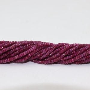 May include: A strand of ruby red faceted gemstone beads. The beads are small and have a slightly irregular shape.