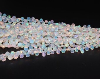 May include: A strand of white opal gemstone beads in a teardrop shape. The beads have a pearlescent iridescent sheen.