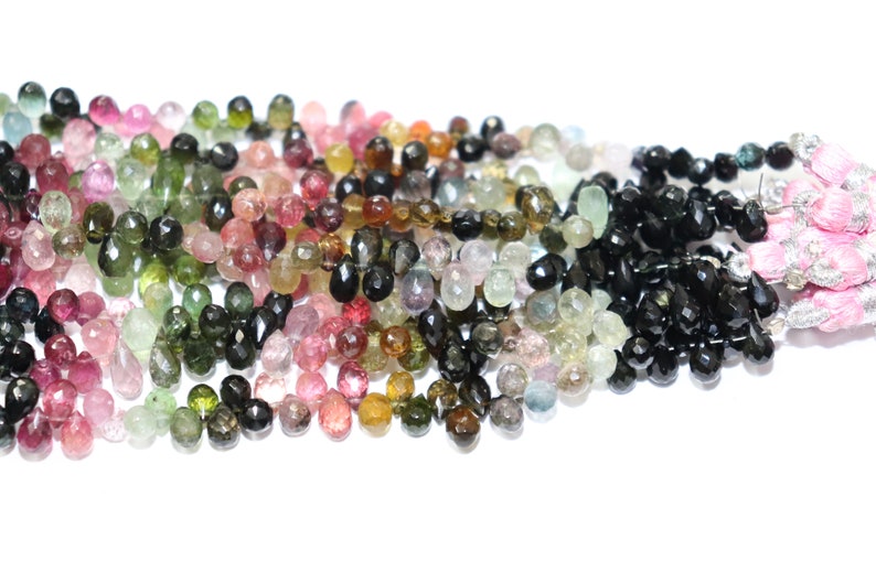 Puede incluir: Una hebra de cuentas de piedras preciosas facetadas en varios colores, incluyendo rosa, verde, negro y marr&oacute;n. Las cuentas tienen forma de l&aacute;grima y tienen un acabado brillante.