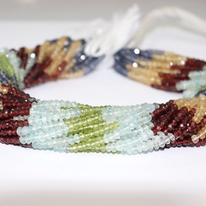 May include: A strand of gemstone beads in a variety of colors, including blue, green, yellow, and red. The beads are faceted and have a smooth, polished finish.
