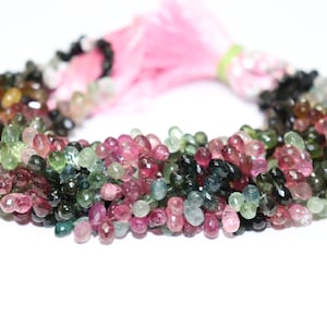 Puede incluir: Una hebra de cuentas de piedras preciosas multicolores. Las cuentas son facetadas y tienen forma de l&aacute;grima. Los colores de las cuentas son rosa, verde y negro.