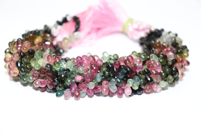 Puede incluir: Una hebra de cuentas de piedras preciosas multicolores. Las cuentas son facetadas y tienen forma de l&aacute;grima. Los colores de las cuentas son rosa, verde y negro.