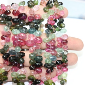 Puede incluir: Una hebra de cuentas de piedras preciosas facetadas en forma de l&aacute;grima en varios tonos de rosa, verde y negro. Las cuentas est&aacute;n enhebradas en un hilo transparente y tienen aproximadamente 6 mm de tama&ntilde;o.