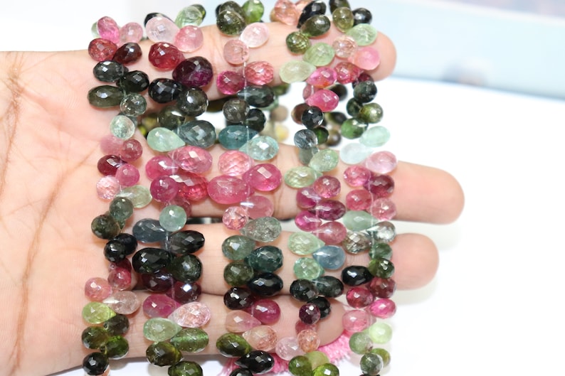 Puede incluir: Una hebra de cuentas de piedras preciosas facetadas en forma de l&aacute;grima en varios tonos de rosa, verde y negro. Las cuentas est&aacute;n enhebradas en un hilo transparente y tienen aproximadamente 6 mm de tama&ntilde;o.