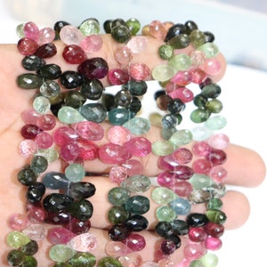Puede incluir: Una hebra de cuentas de piedras preciosas facetadas multicolores. Las cuentas son en tonos de rosa, verde, negro y azul. Las cuentas son de forma ovalada y tienen un acabado facetado.