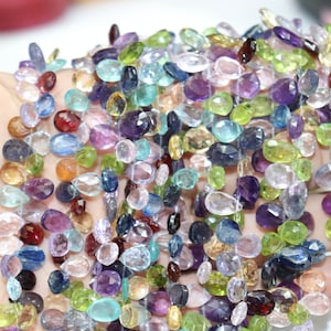 Puede incluir: Una hebra de cuentas de piedras preciosas de colores, con una variedad de formas y tamaños. Las cuentas son una mezcla de piedras azules, verdes, moradas y transparentes.