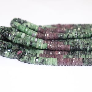 May include: Strands of faceted beads in shades of green and burgundy. The beads are small, square-shaped, and strung together, creating a textured and colorful display. The beads are likely gemstones, perfect for jewelry making.