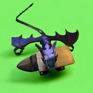 May include: A black and purple dragon figurine with wings, a tail, and a head with a textured design. The dragon is mounted on a wooden base.