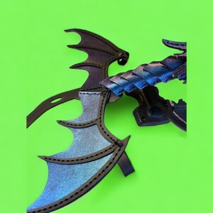 May include: A black leather dragon wing with iridescent blue and purple accents. The wing is attached to a black stand.