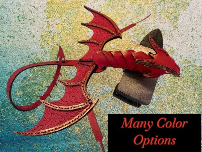 May include: Red leather dragon wings with gold accents and a tail. The wings are attached to a leather strap. The dragon wings are a decorative piece for a costume or cosplay.