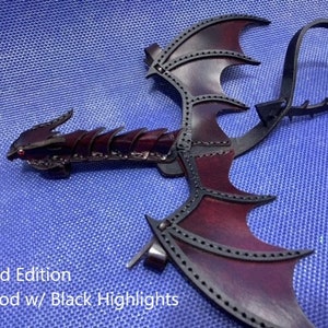 May include: Limited Edition Oxblood leather dragon wings with black highlights. The wings are attached to a leather strap.