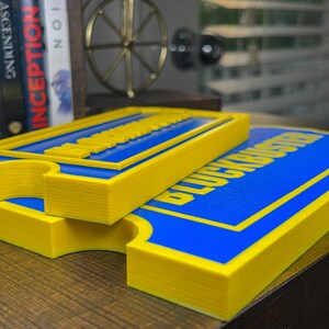 May include: Two yellow and blue signs with the text "Blockbuster" printed on them. The signs are stacked on top of each other.