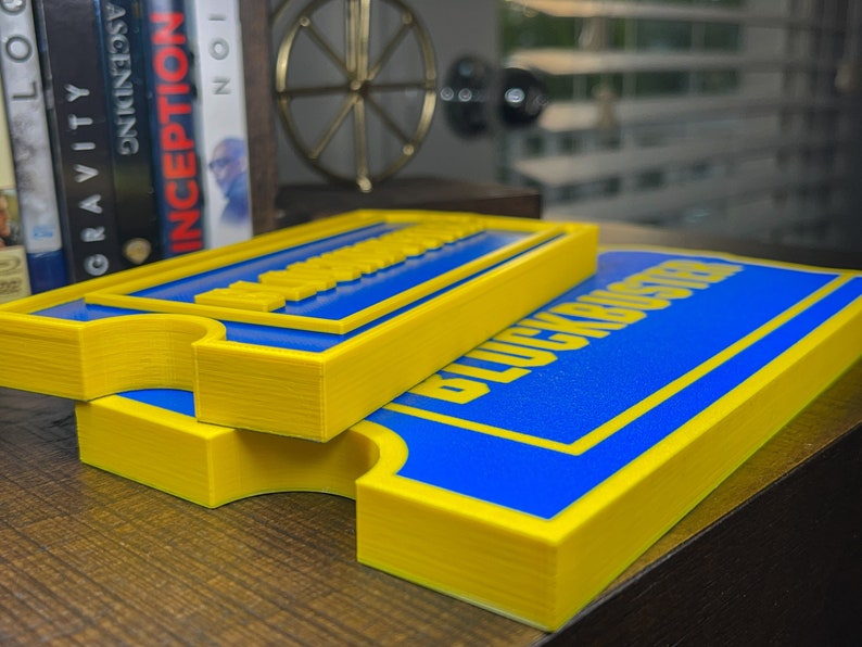 May include: Two yellow and blue signs with the text "Blockbuster" printed on them. The signs are stacked on top of each other.