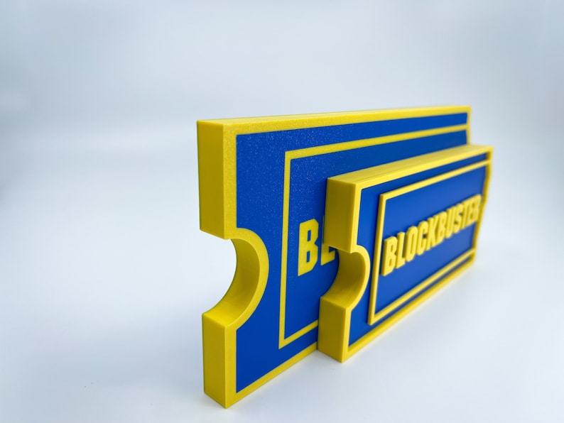 May include: A blue and yellow 3D printed sign that reads "BLOCKBUSTER".