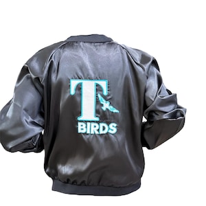 May include: Black satin bomber jacket with the text "T BIRDS" in a teal and white design. The jacket has a teal bird graphic and a black ribbed hem and cuffs. The jacket is a classic style.