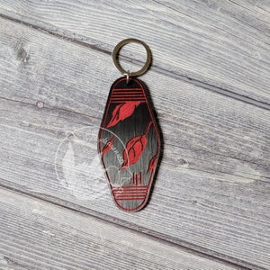 May include: Black motel key chain with red leaf design and the letter "H" on the bottom.