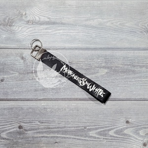 May include: Black key chain with a silver key ring and the text "Motionless In White" printed in white.
