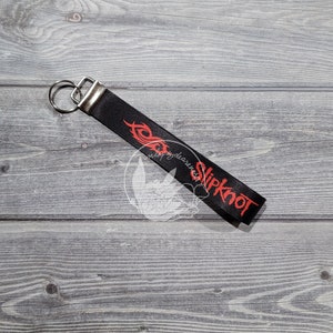 May include: Black and red key chain with the word "Slipknot" printed on it.