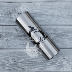 May include: A stainless steel tumbler with a black and white graphic of two rabbits in a circle. The graphic is centered on the tumbler.
