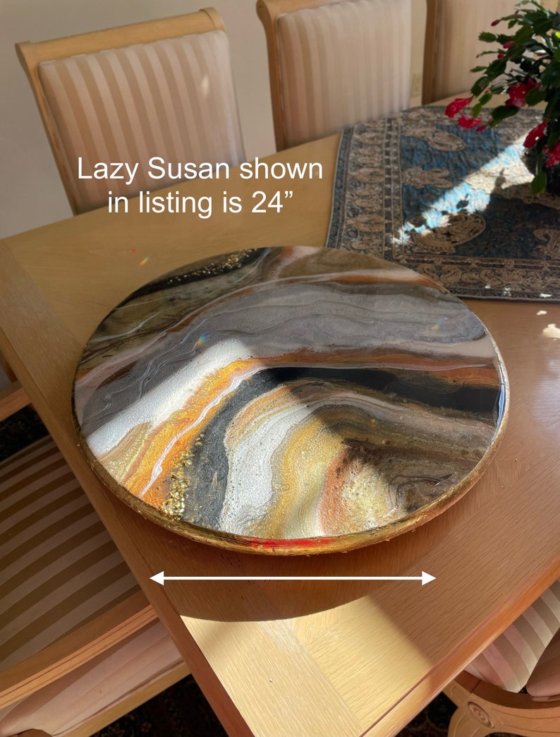 Puede incluir: Una Lazy Susan redonda de 61 cm de di&aacute;metro con un borde dorado y un dise&ntilde;o abstracto en espiral en resina negra, blanca, dorada y marr&oacute;n.