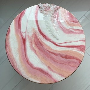 May include: A round, pink and white resin table top with a swirl pattern and embedded crystals.