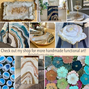 May include: A collection of resin art pieces including rectangular and circular trays, a two-tiered stand, wall art panels, and flower-shaped coasters. The items feature white, blue, teal, and gold metallic accents with textured edges.