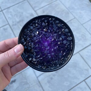 May include: A round black coaster with a purple and black glitter design.