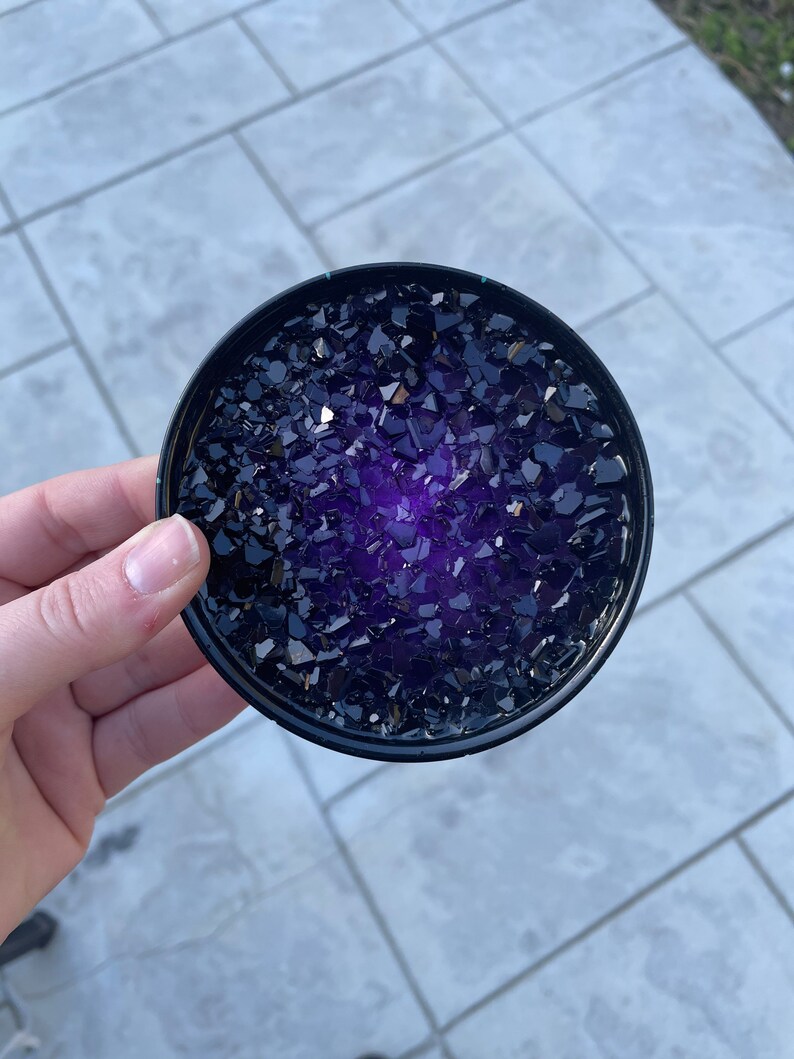 May include: A round black coaster with a purple and black glitter design.