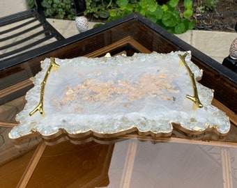 May include: A white resin serving tray with gold accents and a gold-painted wood handle. The tray is filled with small, clear glass pieces.